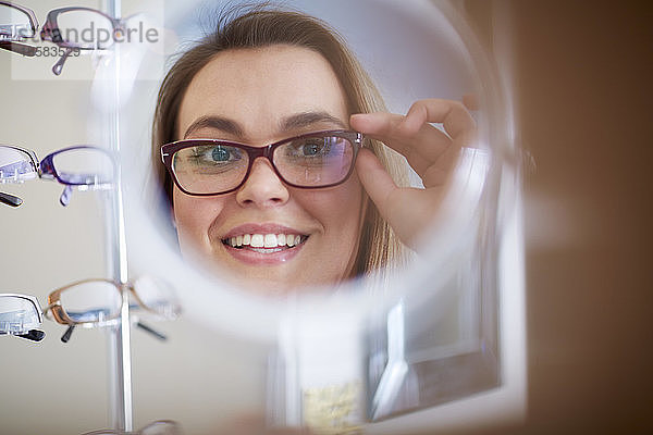 Frau beim Optiker,  die eine Brille anprobiert