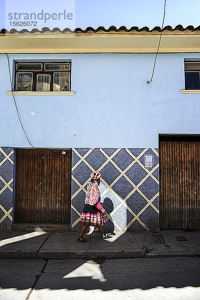 Eine junge Quechuan-Frau,  die eine Straße in Urubamba,  Peru,  entlanggeht