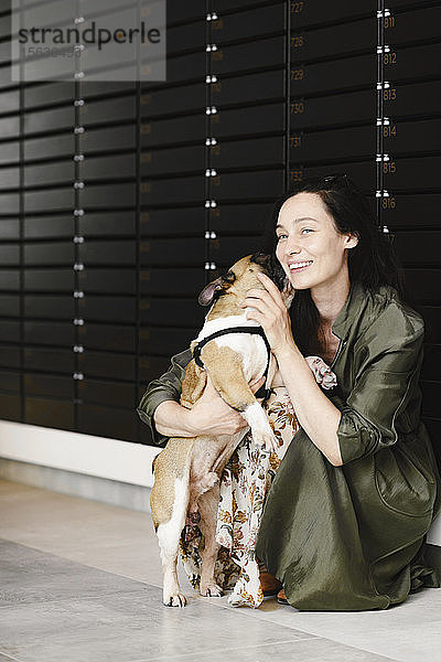 Porträt einer glücklichen Frau,  die ihren Hund kuschelt