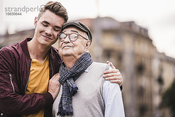 Porträt eines glücklichen älteren Mannes Kopf an Kopf mit seinem erwachsenen Enkel