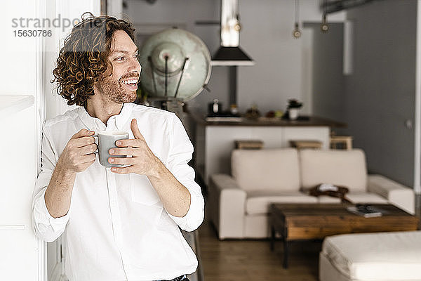 Glücklicher Mann trinkt zu Hause Kaffee