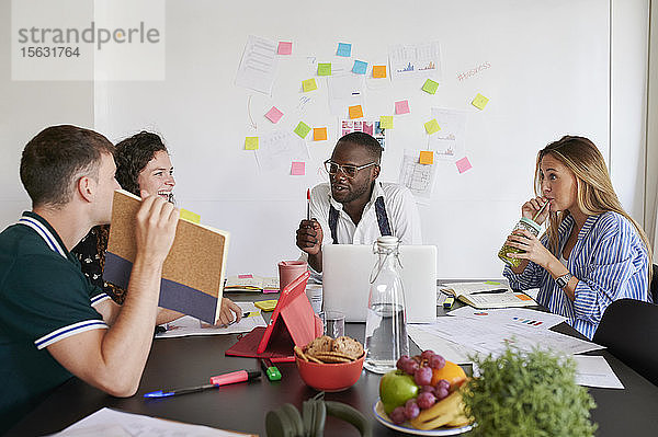 Junge Geschäftsleute beim gemeinsamen Brainstorming um einen Tisch in einem Büro