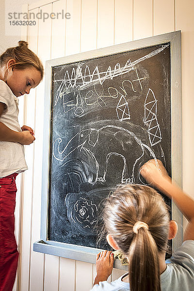 Zwei Mädchen zeichnen auf Tafel