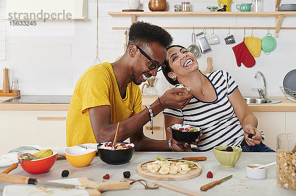 Multiethnisches Paar lacht,  frühstückt gemeinsam in der Küche