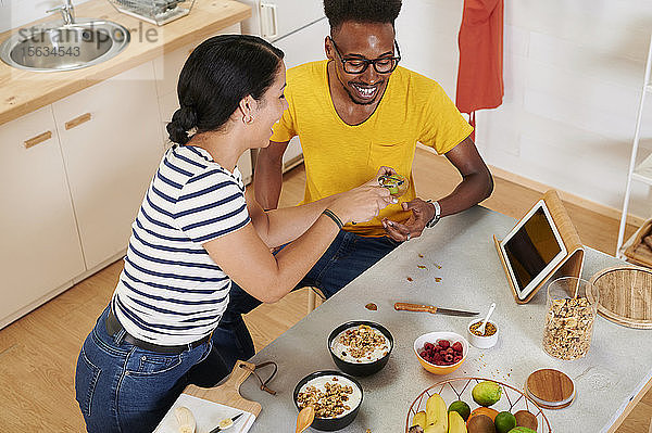 Multiethnisches Paar frühstückt gemeinsam in der Küche,  Talbet im Halter