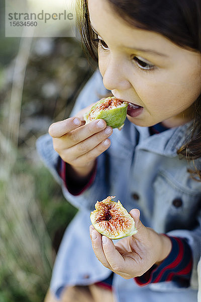Kind isst eine Feige im Freien