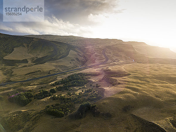Island,  Luftaufnahme einer leeren Straße über braune Hügel bei Sonnenuntergang