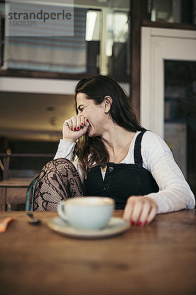 Lachende Frau sitzt in einem Café