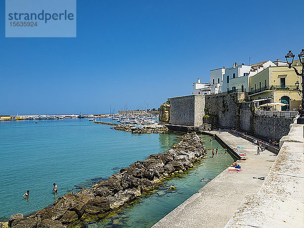 Italien,  Provinz Lecce,  Otranto,  Menschen,  die sich im Sommer am Ufer einer Küstenstadt entspannen