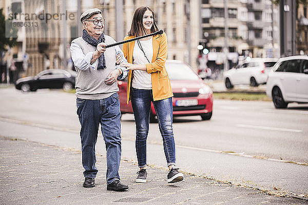 Erwachsene Enkelin,  die ihrem Großvater beim Laufen hilft