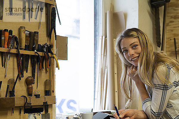 Frau schreibt in einer Werkstatt auf einen Notizblock