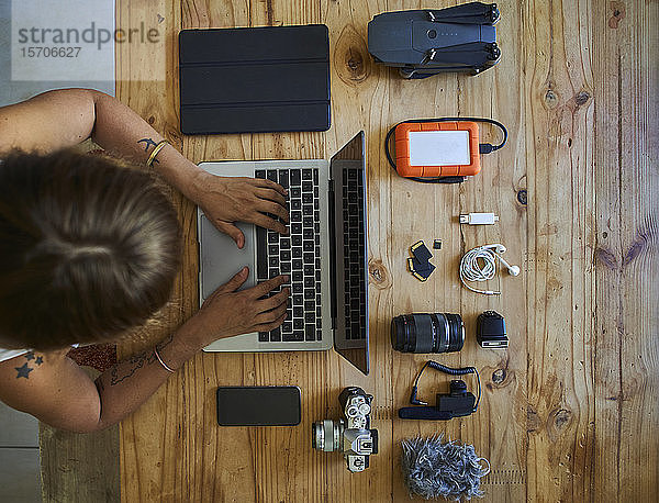 Person am Tisch sitzend mit fotografischer Ausrüstung,  mit Laptop,  Draufsicht