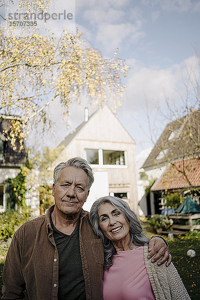 Porträt eines älteren Ehepaares im Garten ihres Hauses im Herbst