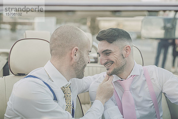 Glückliches elegantes schwules Paar in einem Oldtimer-Cabriolet