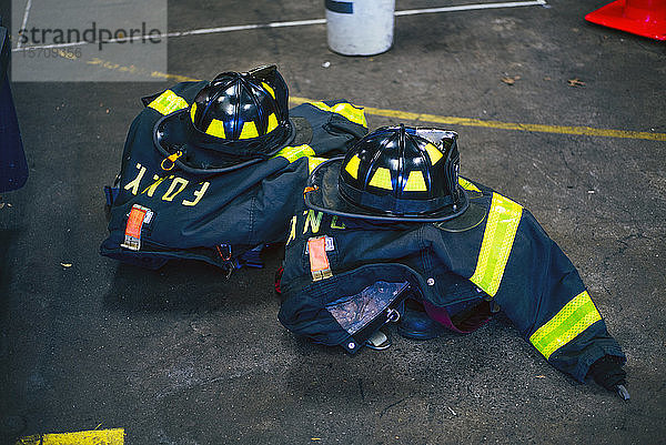 Feuerwehruniformen und -helme in der Feuerwache,  New York,  Vereinigte Staaten