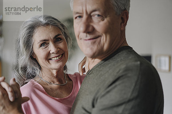 Porträt eines glücklichen Seniorenpaares,  das zu Hause tanzt