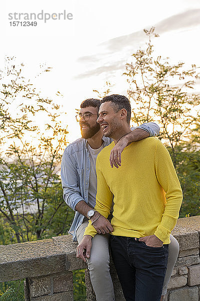 Glückliches schwules Paar bei Sonnenuntergang im Freien