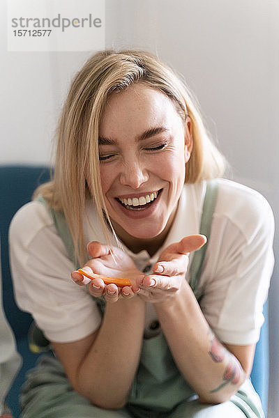 Glückliche junge Frau hält ein Karottenstück