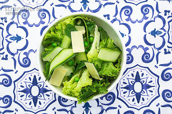 Draufsicht auf Erbsen- und Gurkensalat auf gemustertem Tisch