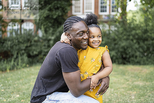 Glücklicher Vater umarmt Tochter in einem Park