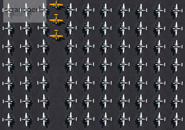 Luftbild von drei orangefarbenen Flugzeugen,  umgeben von ausschließlich weißen Flugzeugen