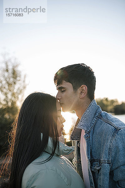 Teenager,  der seine Freundin im Gegenlicht küsst