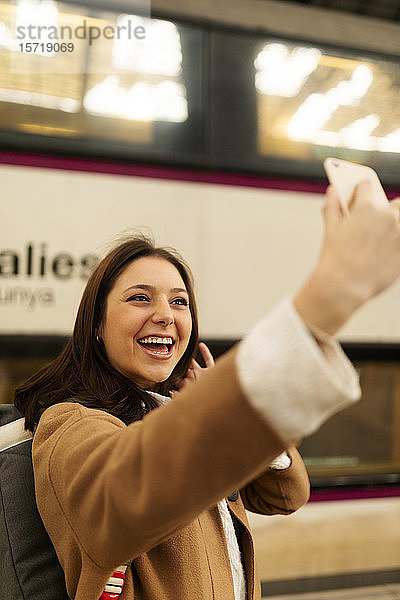 Glückliche junge Frau beim Selfie am Bahnhof