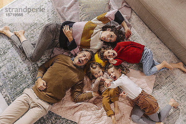 Glückliche Familie mit drei Töchtern,  die zu Hause auf Decken liegen