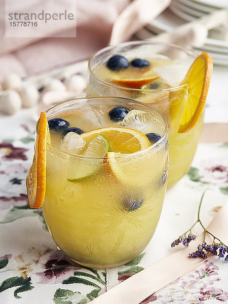 Cocktails mit Orangenscheiben,  Beeren und Eiswürfeln