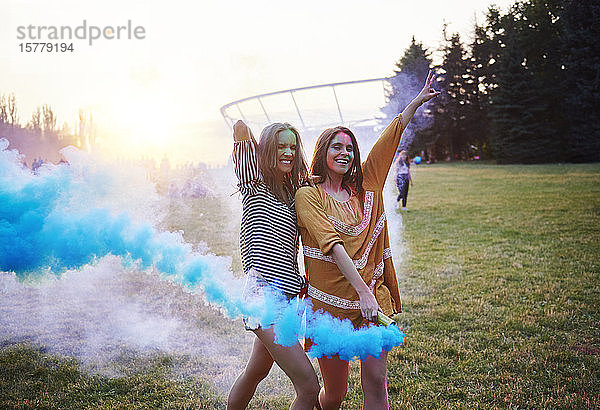 Zwei junge Frauen tanzen mit blauen Rauchbomben beim Holi-Festival