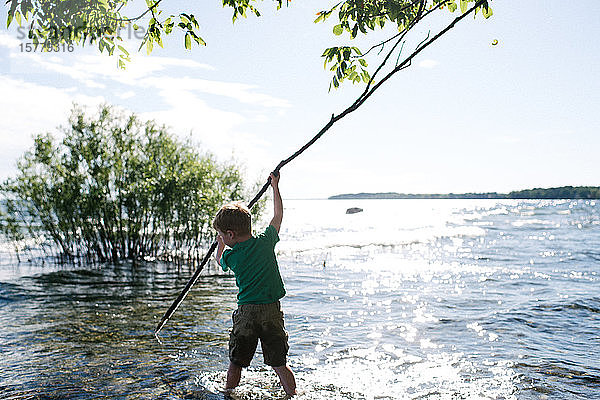 Junge erforscht Wasser mit dem Stock,  Kingston,  Kanada