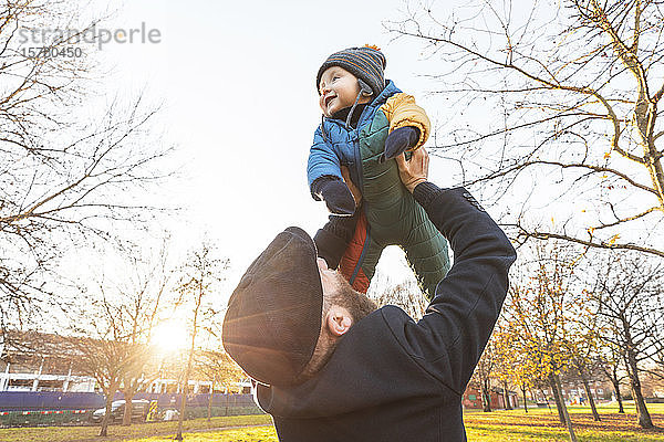 Mann hebt seinen glücklichen kleinen Sohn im Park hoch