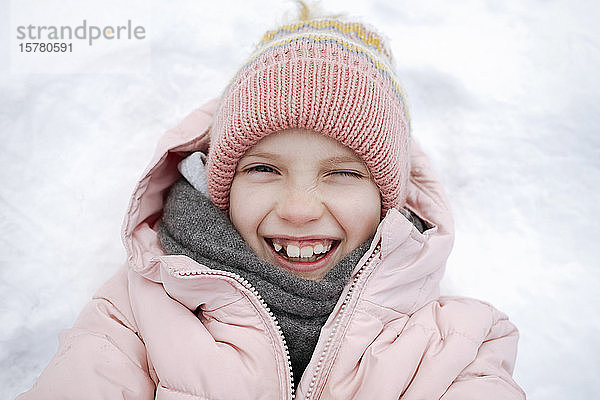 Porträt eines glücklichen Mädchens auf Schnee liegend