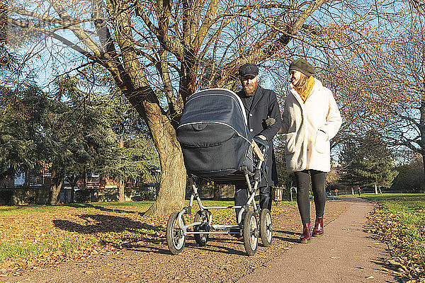 Paar zu Fuß mit Kinderwagen im Park