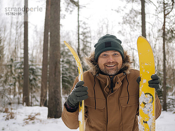 Porträt eines glücklichen Mannes mit Skiern