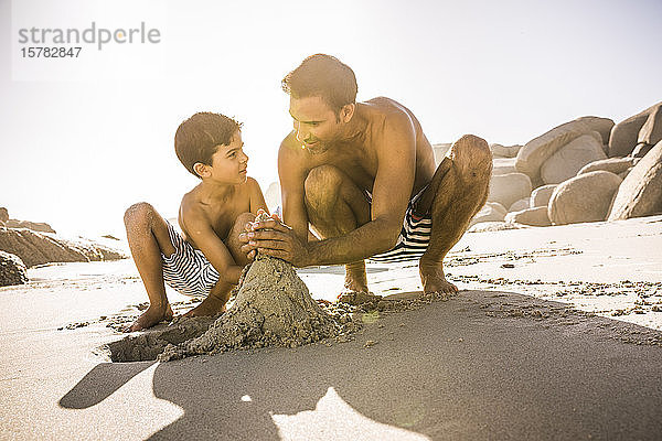 Vater und Sohn bauen gemeinsam eine Sandburg am Strand