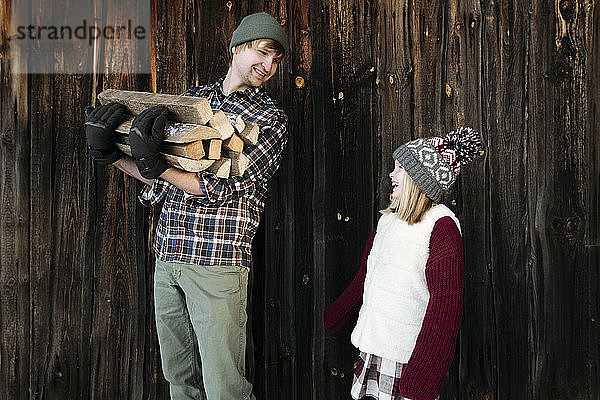 Glückliche Vater und Tochter halten im Winter Brennholz