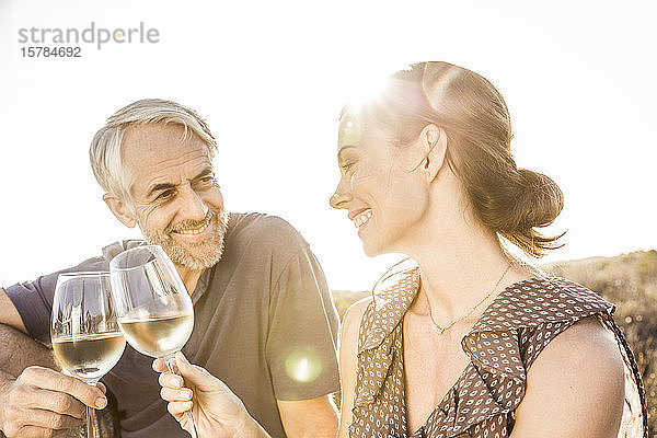 Glückliches Paar trinkt bei Sonnenuntergang ein Glas Weißwein