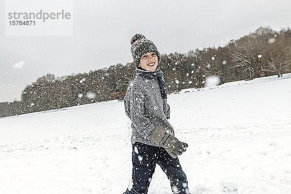 Porträt eines glücklichen Jungen in Winterlandschaft mit Schneefall