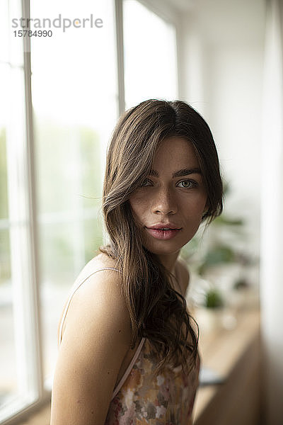 Porträt einer schönen jungen Frau am heimischen Fenster