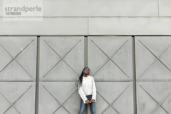 Junge Frau hält eine Tafel an eine graue Wand
