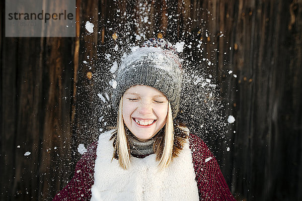 Schnee fällt auf glückliches Mädchen mit Wollmütze