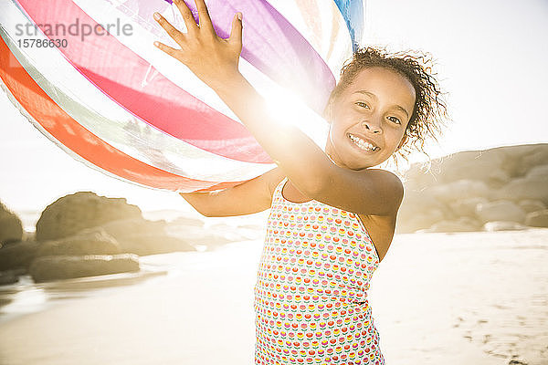 Glückliches Mädchen hält aufblasbaren Ball am Strand