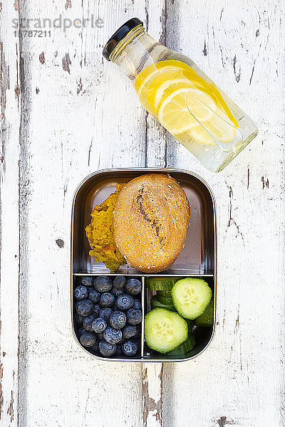Limonadenflasche und Lunchbox mit Gurkenscheiben,  Blaubeeren und Brötchen mit Linsenpaste