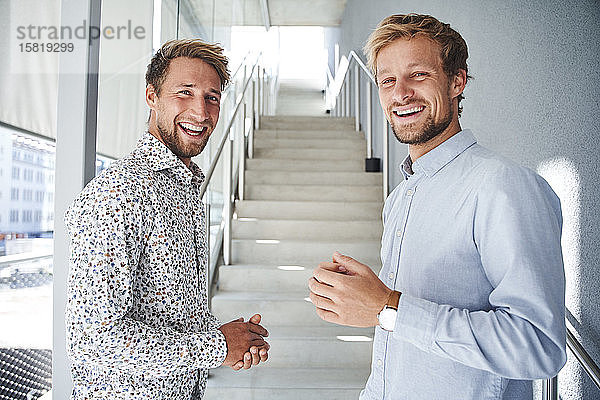 Porträt von zwei glücklichen jungen Geschäftsleuten im Treppenhaus