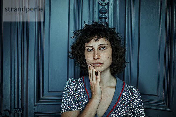 Porträt einer jungen Frau vor blauer Holztür