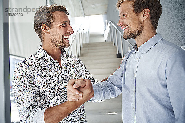 Porträt von zwei glücklichen jungen Geschäftsleuten beim Händeschütteln