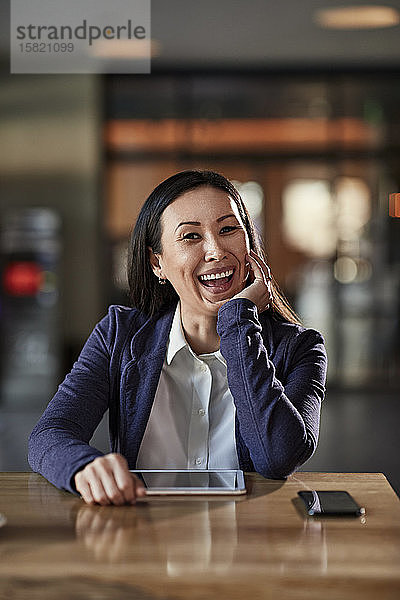 Porträt einer lachenden Geschäftsfrau bei Tisch