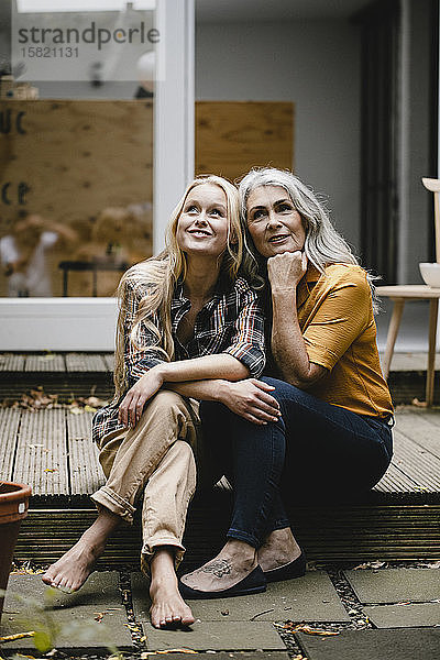 Lächelnde Mutter und erwachsene Tochter sitzen auf der Terrasse