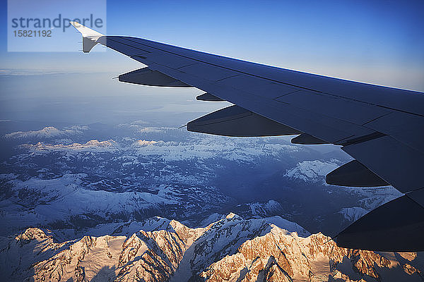 Frankreich,  Auvergne-Rhône-Alpes,  Tragfläche des Airbus A321 im Morgengrauen über den europäischen Alpen und dem Genfer See